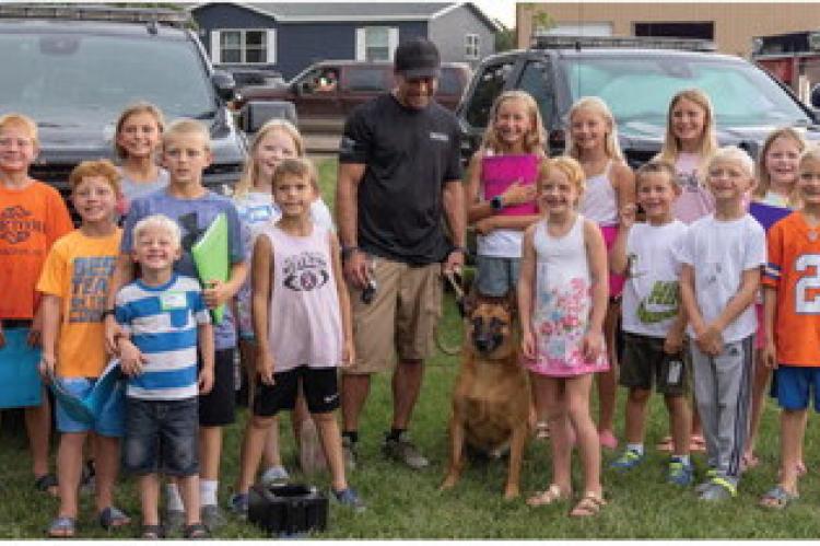 Children pose with Deputy Sheria Joel Neuman and police dog Krome.