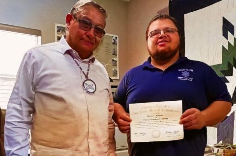 Dallas Tronvold stands with Tribal Chairman Robert Flying Hawk at the Yankton Sioux Tribal Headquarters accepting his congratulations on earning his NREMT accreditation.