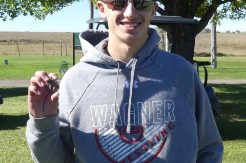 Grady Bartunek holding his medal for 14th place qualifying him for state.
